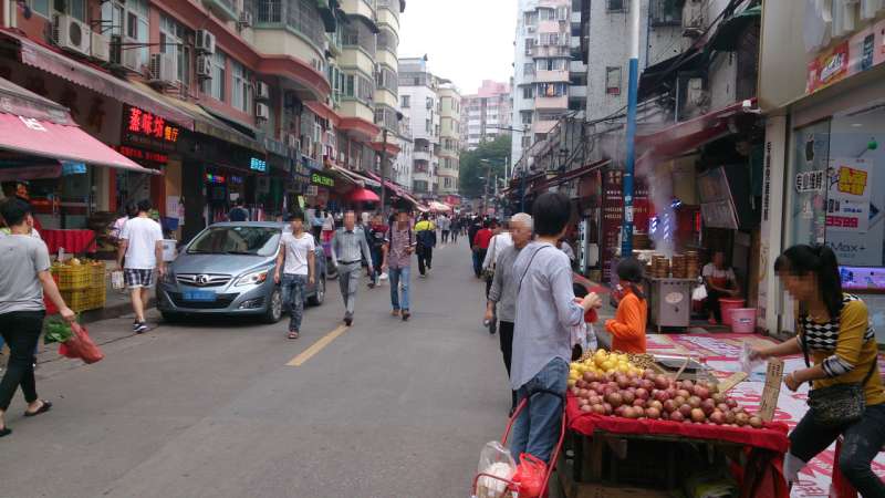広州の街並みで果物の露店がでたり、道を歩いている人がいる